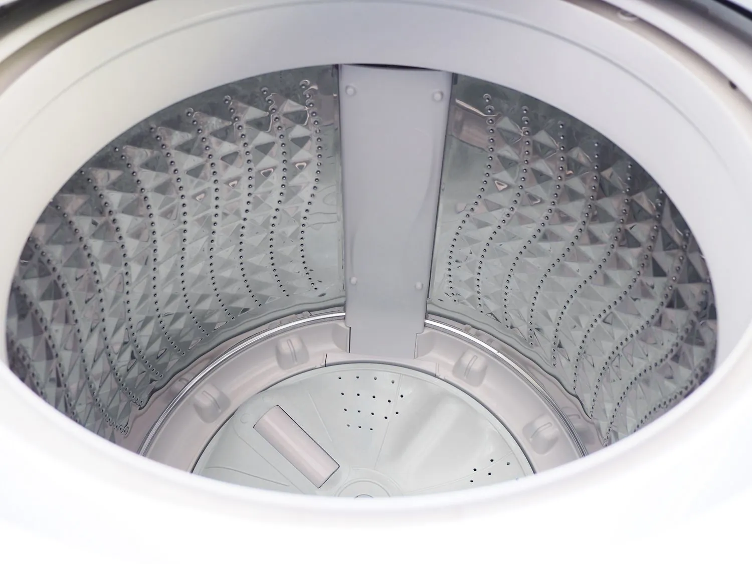 Basic and high-efficiency top loading washing machines side by side in a laundry room