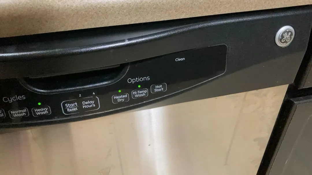 A closed GE dishwasher control panel glowing in a modern kitchen