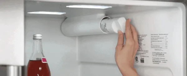 Hand checking the water dispenser on a Frigidaire refrigerator in a kitchen