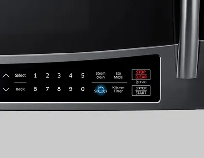 Hand reaching for microwave controls with a phone and notebook nearby