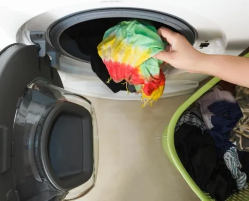 Hand unplugging a dryer power cord from a wall outlet