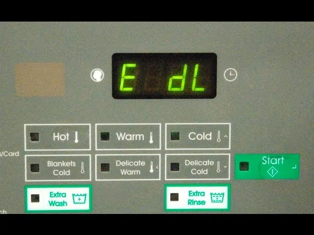 Multimeter and tools beside an open washing machine during a repair