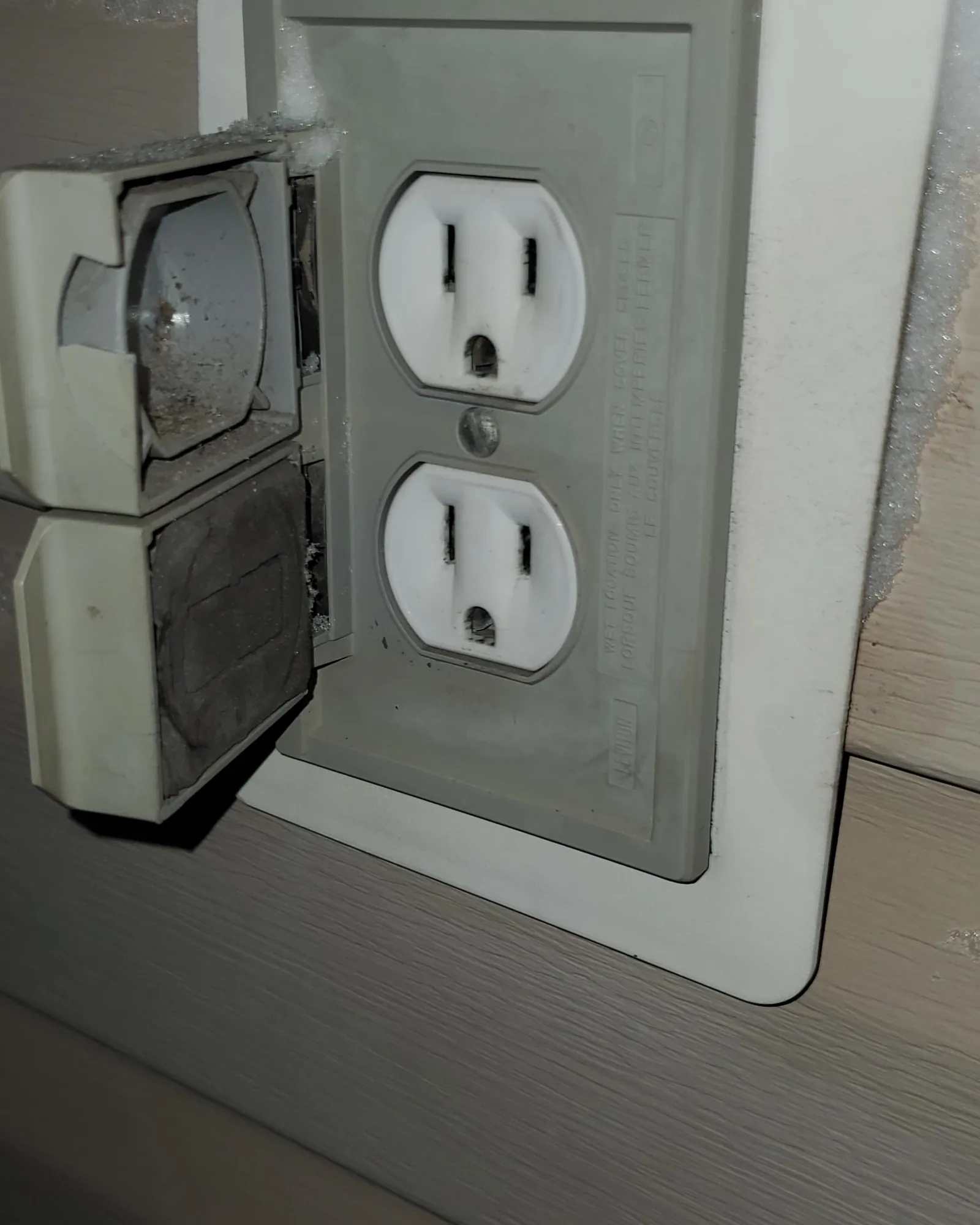 Open breaker panel with tripped breaker beside outdoor outlet box