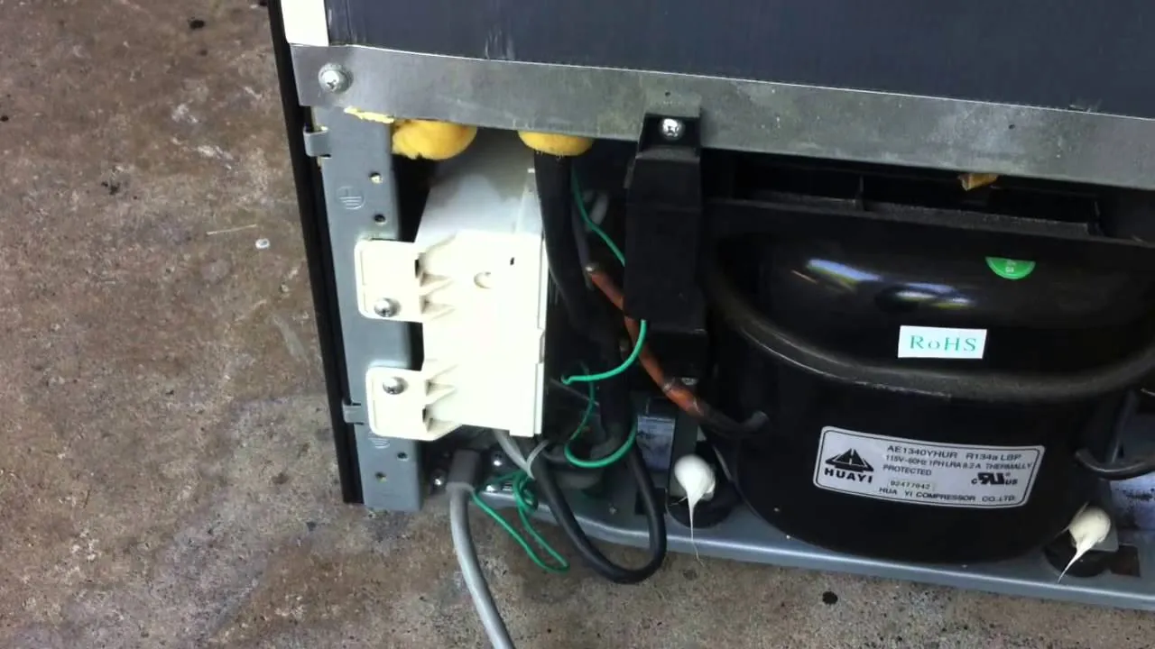 Screwdriver turning defrost timer dial on back of Kenmore freezer