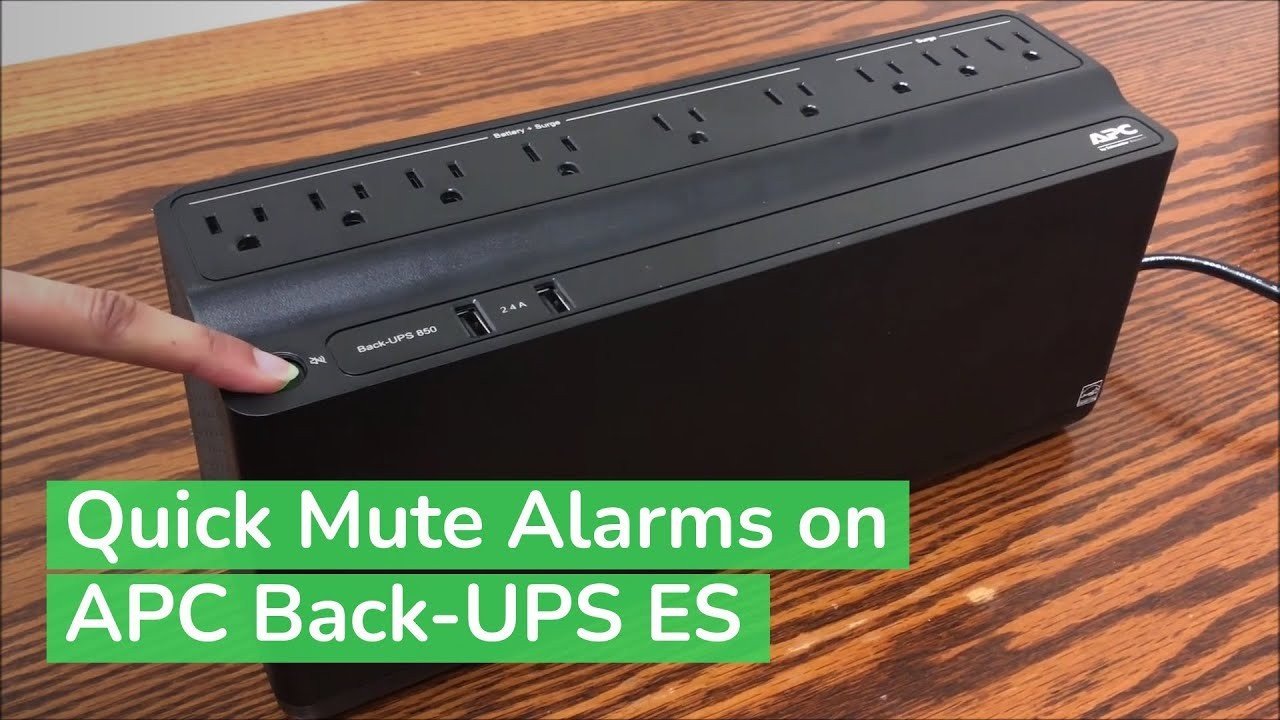 UPS battery backup unit beeping on a wooden floor beside a wall outlet