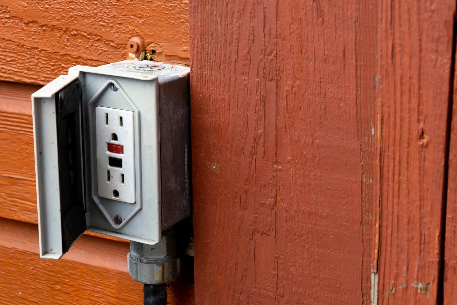 Wet outdoor outlet with cover open showing moisture and debris