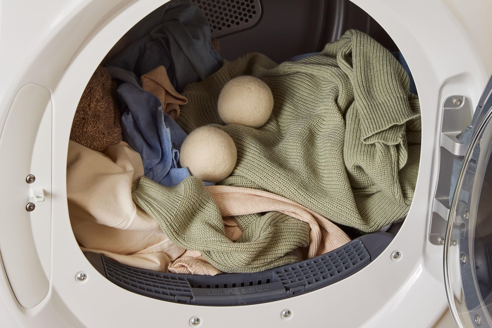 White clothes dryer with door ajar in a bright laundry room