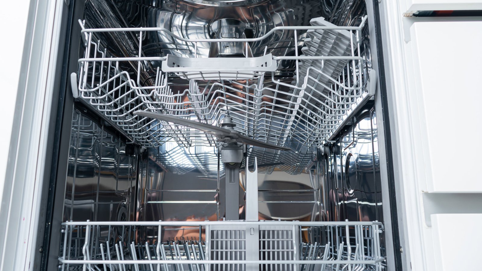 White dishwasher with door ajar under a kitchen counter, humming without water
